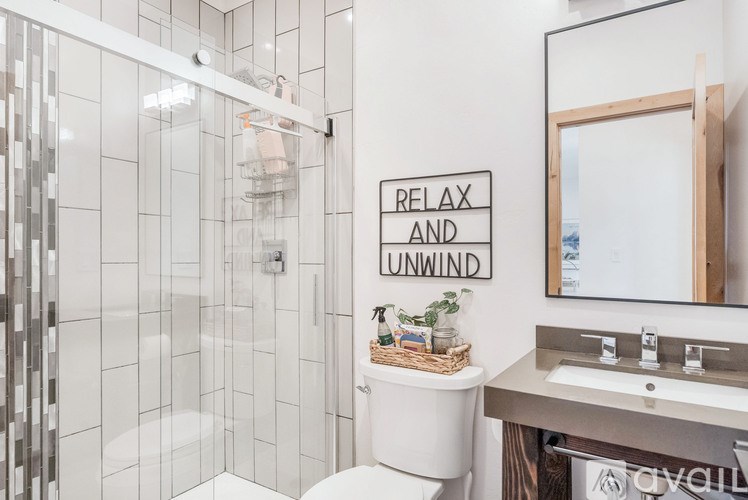 A bathroom with a white toilet, a white sink, and a glass shower stall.