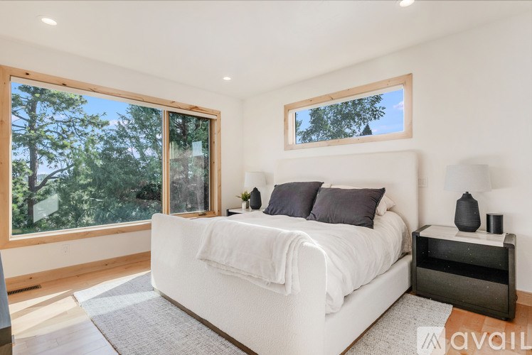 A bedroom with a large bed and a window overlooking trees.