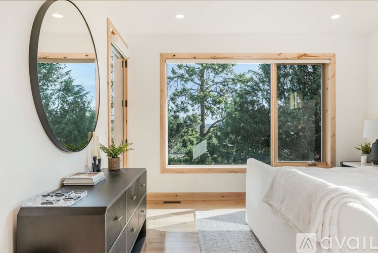 A bedroom with a large window and a white bed.