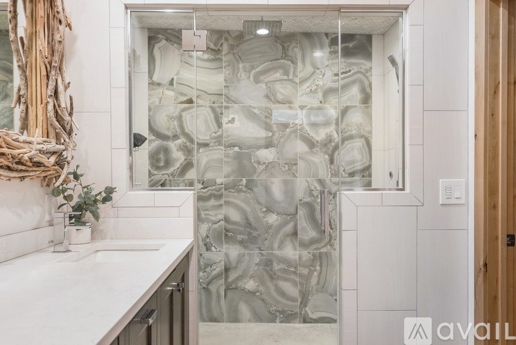 A bathroom with a marble tile shower and a wooden door.