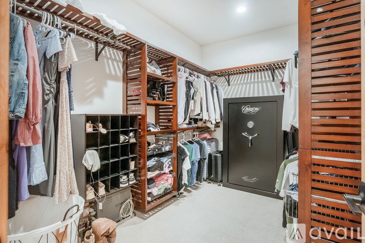 A walk-in closet with clothes and shoes organized on shelves and hangers.