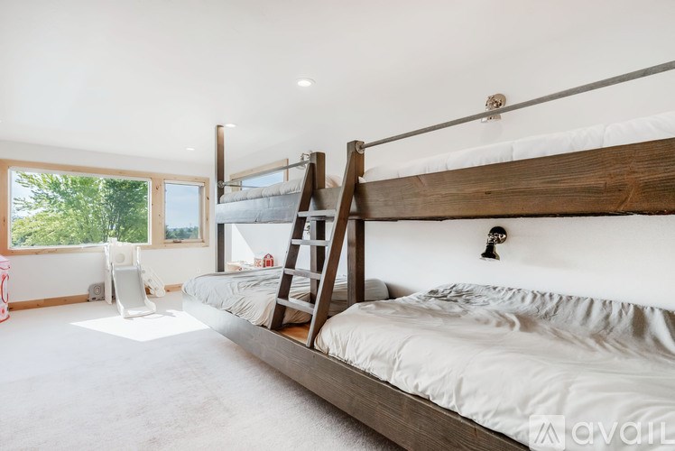 A bedroom with a bed, a ladder, and a window.