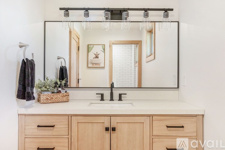 A bathroom with a vanity, mirror, and a basket of flowers.