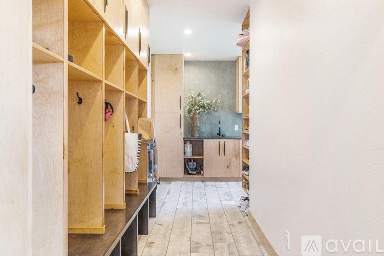 A long hallway with shelves on the side and a door at the end.