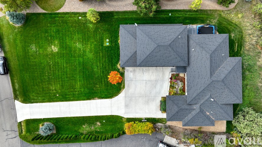 A house with a grey roof is surrounded by a green lawn.