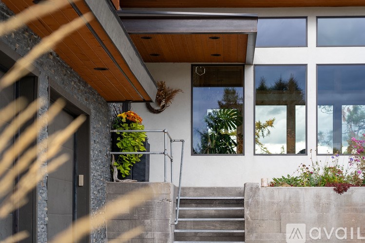 A house with a wooden roof and a stone wall with plants growing on it.