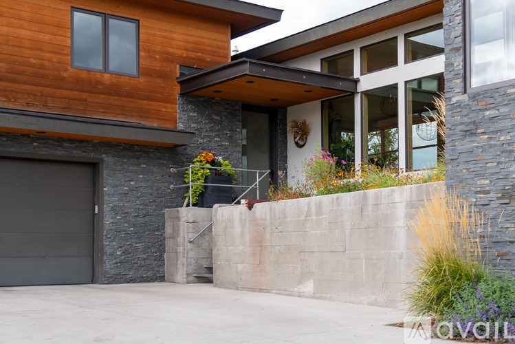 A modern house with a wooden exterior and a stone wall.