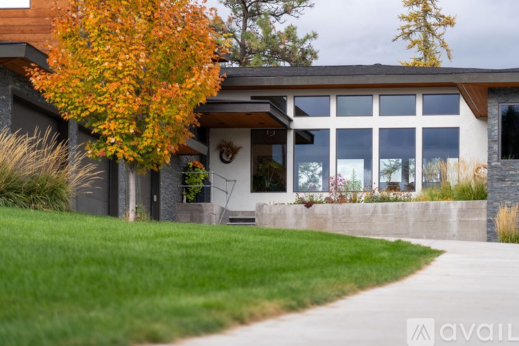 A house with a tree in autumnal colors in front of it.