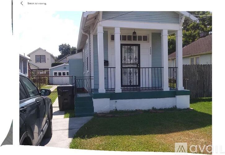 A white house with a black gate and a green lawn.