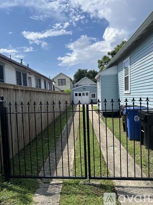 A black metal fence with a gate blocks the view of a residential area.