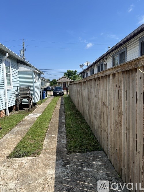 A narrow alley with a wooden fence on one side and houses on the other.