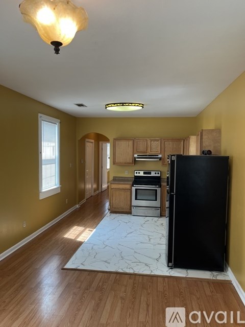 A kitchen with a black refrigerator and wooden cabinets.