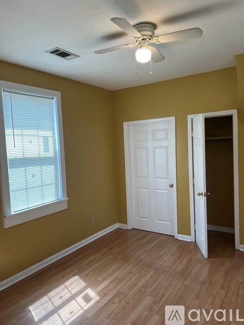 A room with a ceiling fan and a window with blinds.