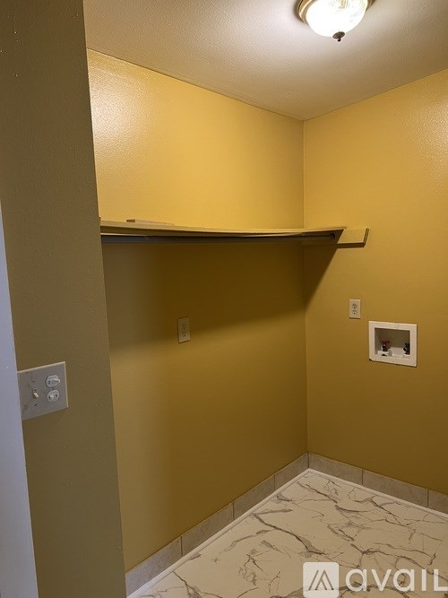 A small room with a marble floor and a shelf above it.