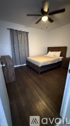 A bedroom with a bed, wooden floor, and a ceiling fan.