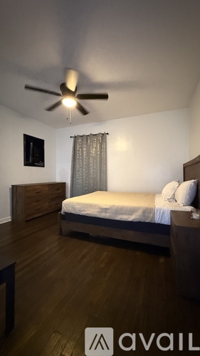 A bedroom with a bed, dresser, and ceiling fan.