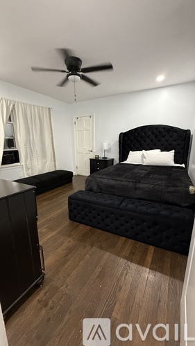 A bedroom with a black bed and a ceiling fan.