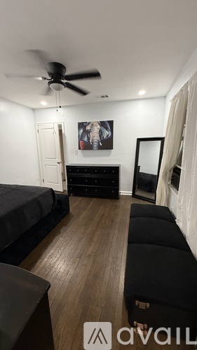 A living room with a black couch and a ceiling fan.