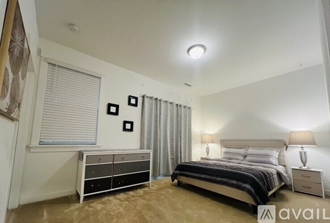 A bedroom with a bed, nightstands, and a window with blinds.