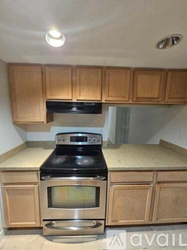 A kitchen with wooden cabinets and a black stove top oven.