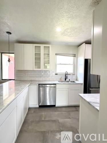 A kitchen with white cabinets and a stainless steel dishwasher.