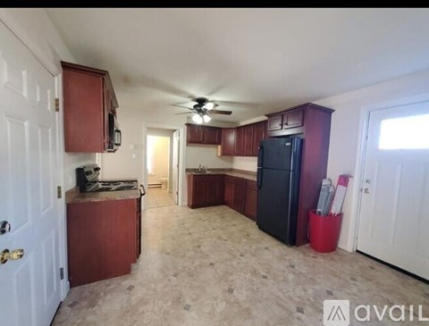 A kitchen with a black refrigerator and wooden cabinets.