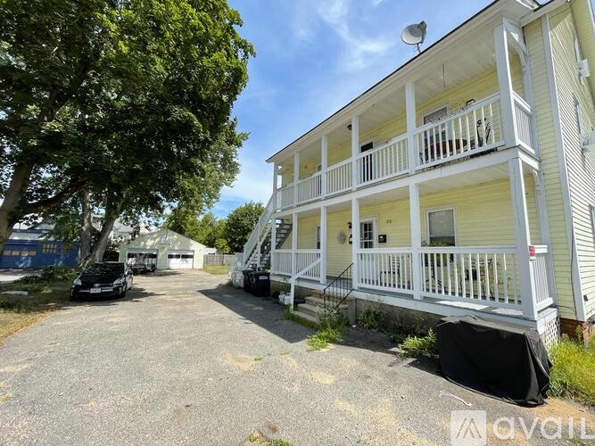 A two-story house with a balcony and a tree in front.