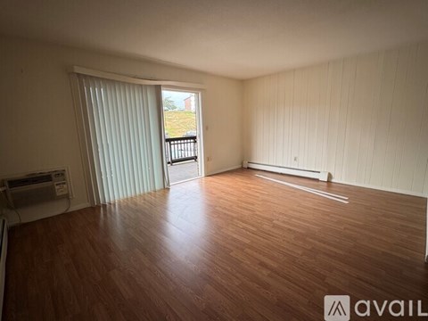 A room with wooden flooring and a sliding glass door leading to a balcony.