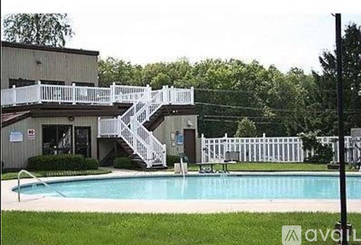 A pool with a white fence and a building with a white staircase.