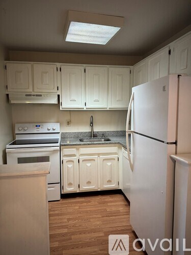 A kitchen with white cabinets and a white refrigerator.
