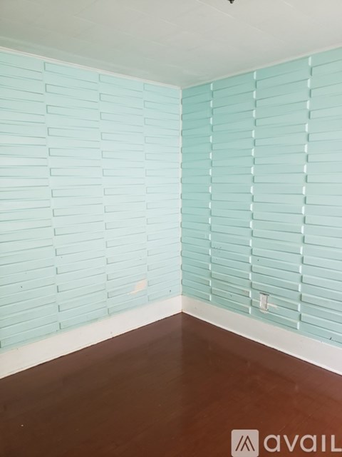 A room with a wooden floor and a wall covered in light blue tiles.