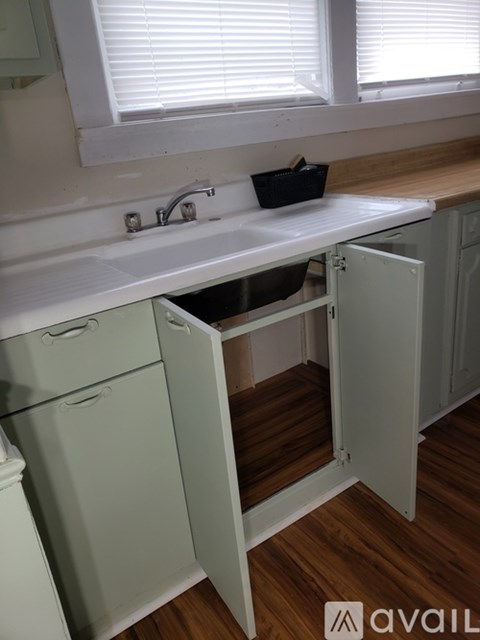 A kitchen with a sink and a cabinet with a drawer pulled out.