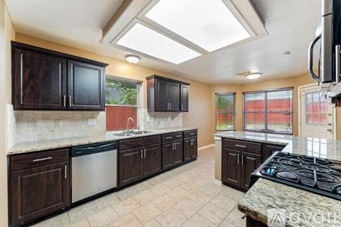 A kitchen with dark wood cabinets and a granite countertop.