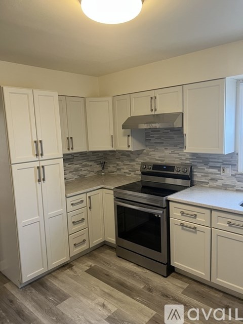 A kitchen with white cabinets and a stone backsplash.