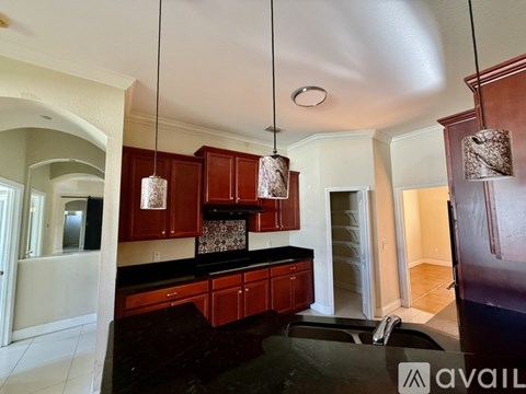 A kitchen with dark wood cabinets and a black countertop.