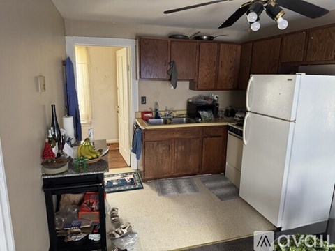 A kitchen with a white refrigerator and wooden cabinets.