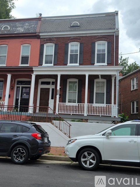 Two cars parked in front of a red brick house.