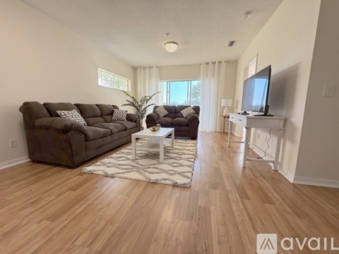 A living room with a brown couch, a white coffee table, and a television on a stand.