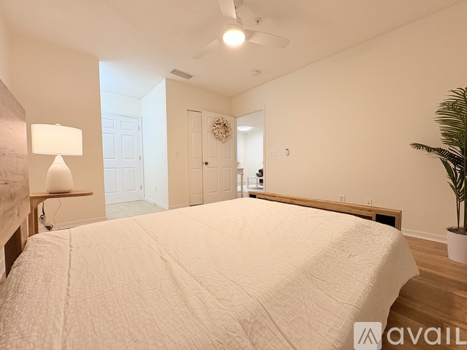 A bedroom with a large bed and a plant on the side table.