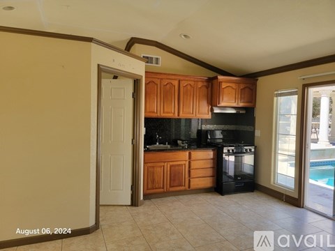 A kitchen with wooden cabinets and black appliances is available for rent.