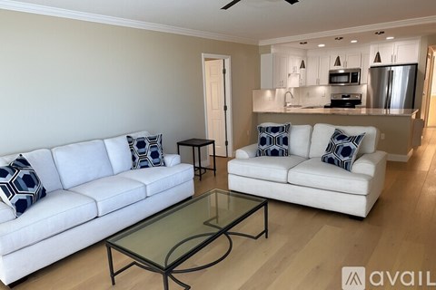 A living room with a white couch and a glass coffee table.