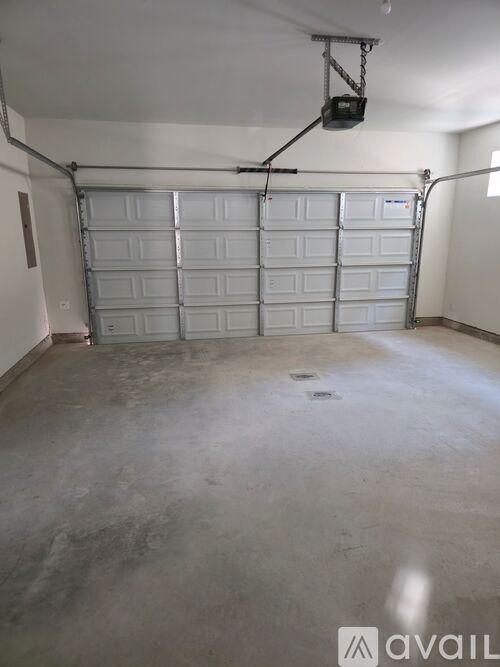 A large garage with a white door and a black speaker hanging from the ceiling.