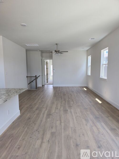 A spacious room with wooden flooring and a ceiling fan.