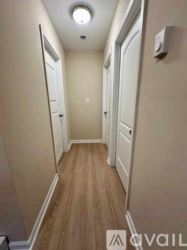A hallway with wood flooring and white walls.