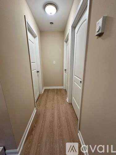 A hallway with wood flooring and white walls.