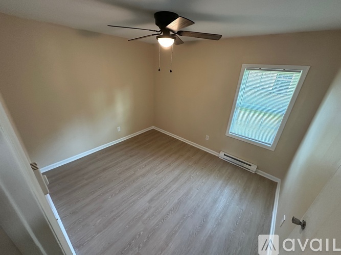 A room with a ceiling fan and a window with blinds.