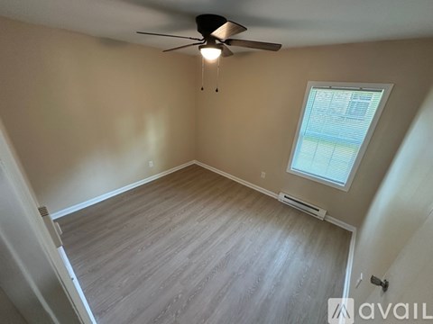 A room with a ceiling fan and a window with blinds.