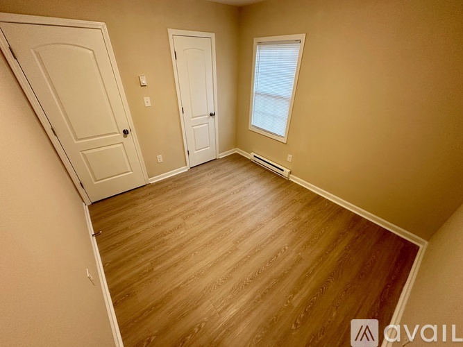 A room with wooden flooring and two doors.