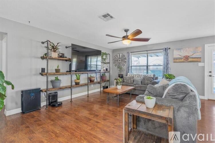 A living room with a grey couch, a wooden coffee table, and a ceiling fan.