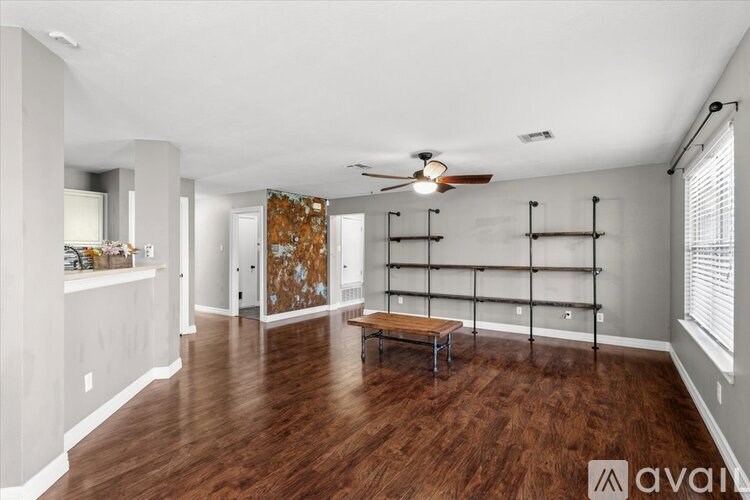 A room with a wooden table and benches, a window with curtains, and a painting on the wall.